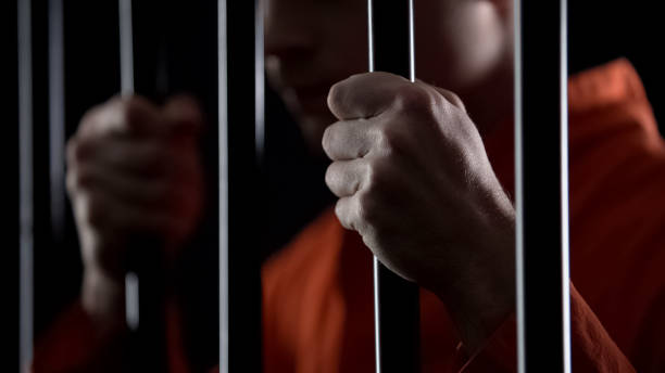 istock Desperate criminal holding jail bars feeling regret for committing crime closeup 1135489412