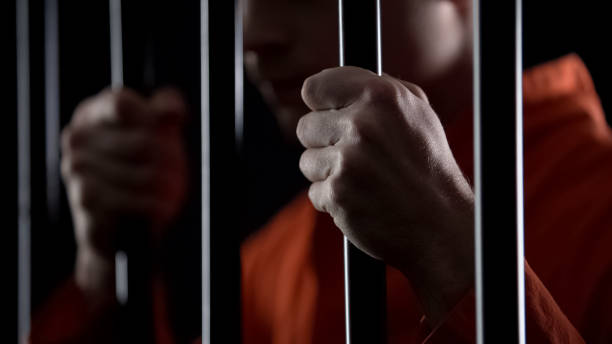 Desperate criminal holding jail bars feeling regret for committing crime closeup Desperate criminal holding jail bars feeling regret for committing crime closeup mass unit of measurement photos stock pictures, royalty-free photos & images