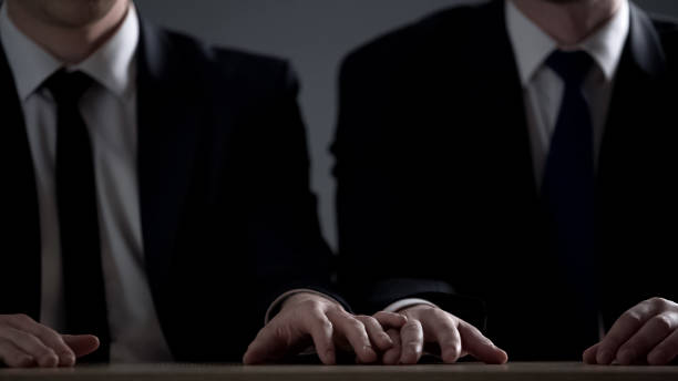 istock Colleagues in suit sitting at table and touching hands, love relationship, flirt 1135489549