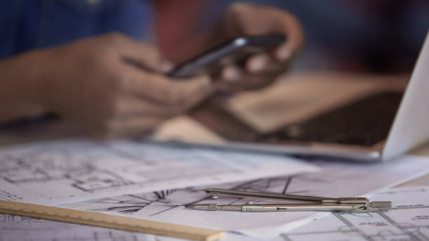 istock Apartment layouts lying on table, female architect typing, scrolling on phone 1135490451