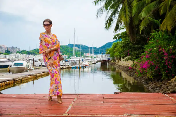 Photo of Cheerful and beautiful girl resting fun in vacation, on the pier with boats. In China, Hainan city of Sanya. View of island in bay. Town Sanya is popular tourist destination in China