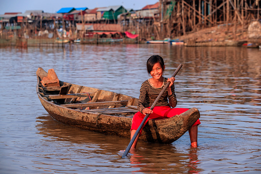 Cambodian little girl rowing a boat on Tonle Sap, Cambodia