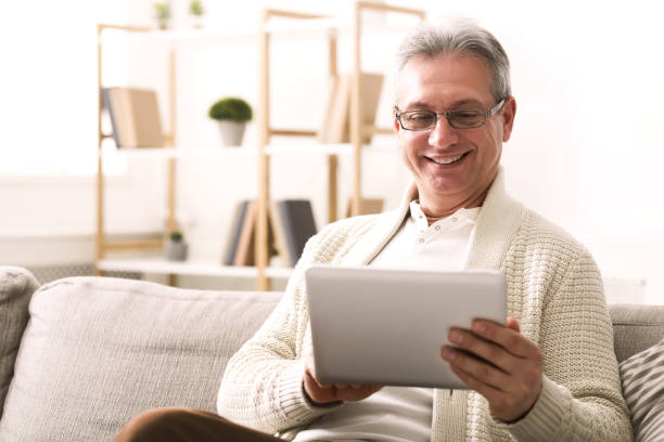 istock Mature man websurfing in digital tablet at home 1135496427