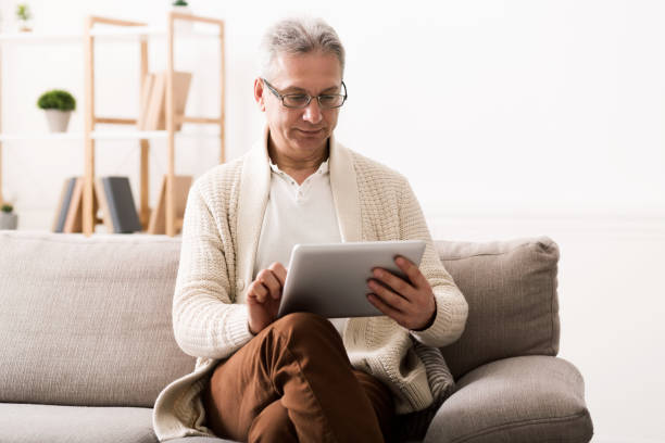 istock Mature man reading news on tablet at home 1135496432