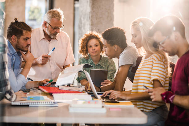 istock Mature professor teaching group of college students at campus. 1135498526