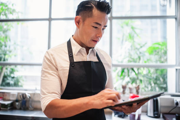 istock Chinese male barista using digital tablet at work 1135498930
