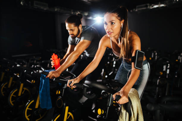 istock Two young people exercising on exercise bike at gym 1135499096