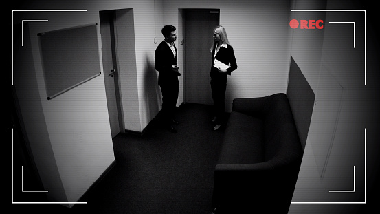 Male and female colleagues talking office corridor, CCTV camera effect, footage