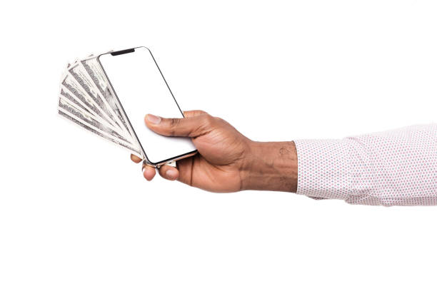 istock Male hand holding blank cellphone and USD banknotes 1135500346