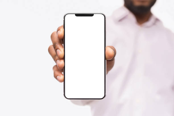Businessman showing smart phone, with copy space Black businessman showing smartphone with blank screen, isolated on white background, copy space hand holding phone stock pictures, royalty-free photos & images