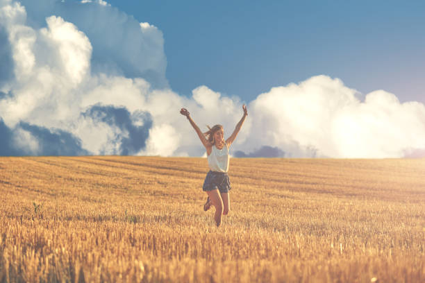 Young woman jumping and running in a wheat field.