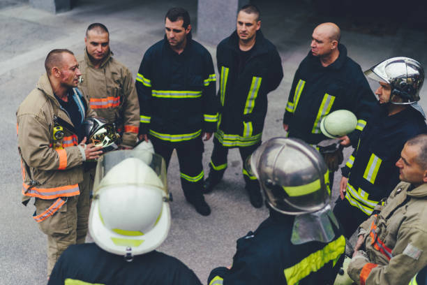 Team of firefighters listening to instructions Group of real firefighters on training standing in circle team event stock pictures, royalty-free photos & images