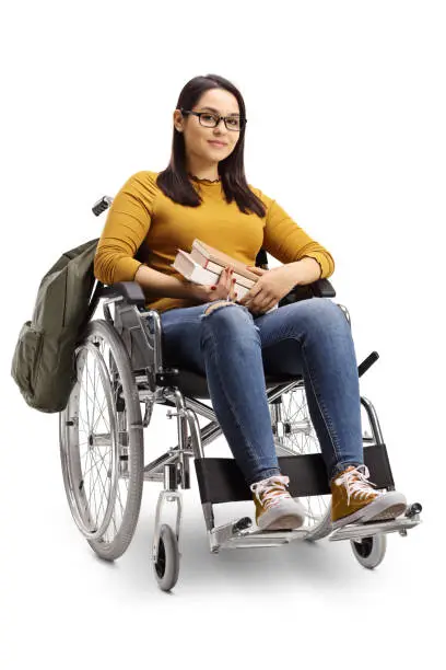 Full length shot of a female student in a wheelchair holding books isolated on white background