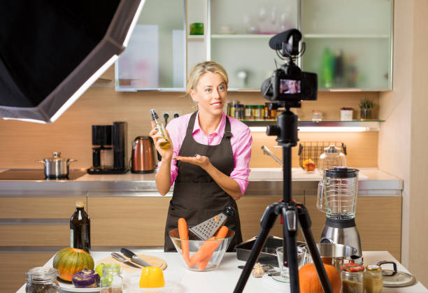 Woman recording video in her home kitchen, creating content for video blog Young female recording video in her home kitchen, creating content for video blog cooking show stock pictures, royalty-free photos & images