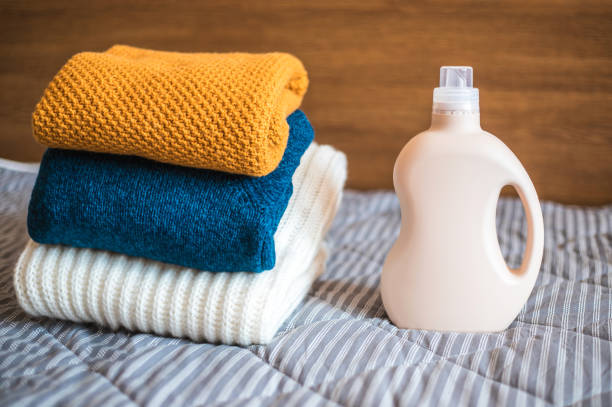 bottle of detergent and a pile of sweaters. - liquid soap blue plastic textile imagens e fotografias de stock