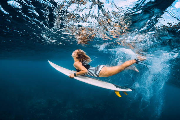 istock Surfer woman dive underwater. Surfgirl dive under big wave 1135512110
