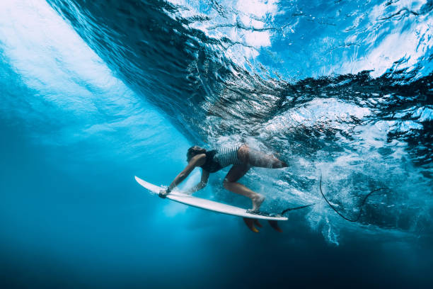 istock Surfer woman dive underwater. Surfgirl dive under big wave 1135512216