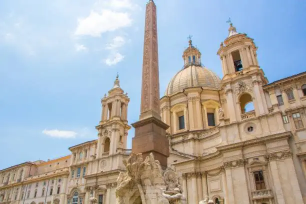Fountain of the Four Rivers with an Egyptian obelisk and Sant Agnese Church on the famous Piazza Navona Square. Sunny summer day. Rome, Italy. Architecture and sights of Rome.