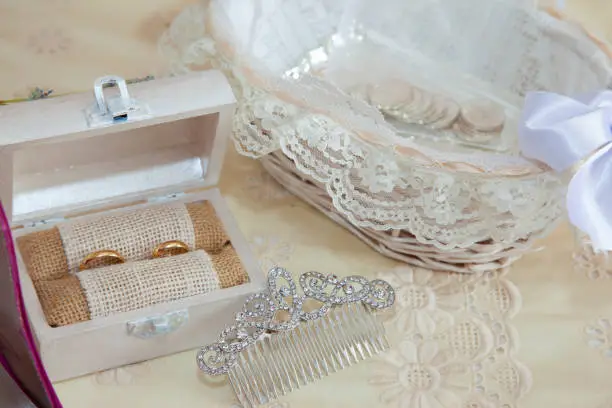 still life on the double bed of the accessories of a bride with arras, a wooden box with the wedding rings and a hair ornament