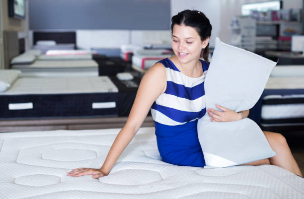 istock Female sitting with pillow on mattress 1135516137