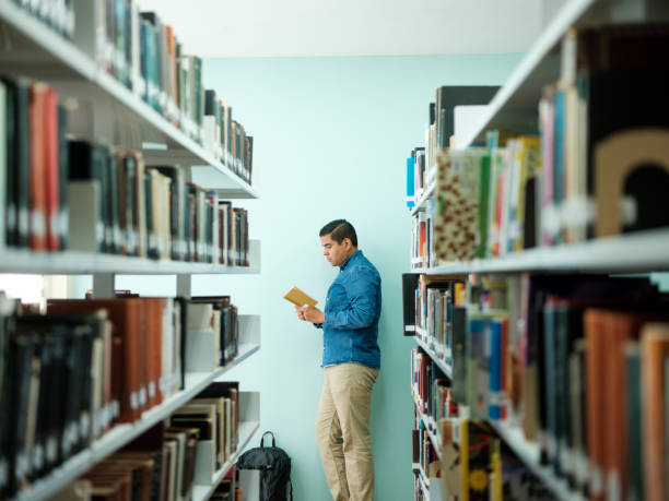 istock Male college student reading a book standing 1135517408