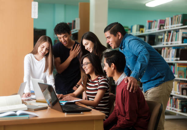 istock Happy college friends looking at laptop together 1135517424