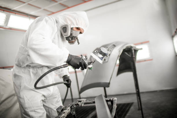 istock Professional car painter blasting a car bumper damaged in an accident with a base coat paint in a workshop 1135517873