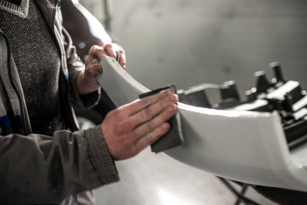 car repair technician using a sanding paper to remove excess filling form a car bumper that got damaged in accident - bumper imagens e fotografias de stock