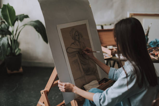 istock Long haired lady drawing on the canvas in art studio 1135519633