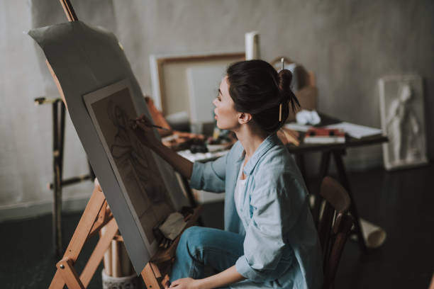 istock Beautiful lady drawing on the canvas while being alone in her studio 1135519646