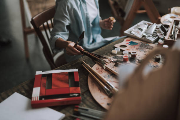 istock Female artist with spatula taking paintbrushes from the table 1135519700