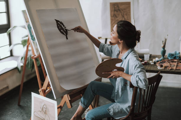 istock Calm young lady drawing leaf on the white canvas 1135519717
