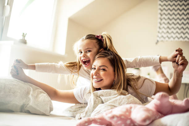 istock Mother and daughter having piggyback ride in bed. 1135520463