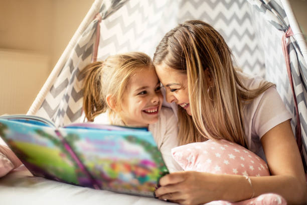 madre che legge una storia a sua figlia. - child reading mother book foto e immagini stock