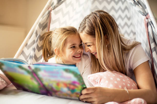 Mother reading a story to her daughter. Loving mother reading a story to her cute daughter. tent photos stock pictures, royalty-free photos & images