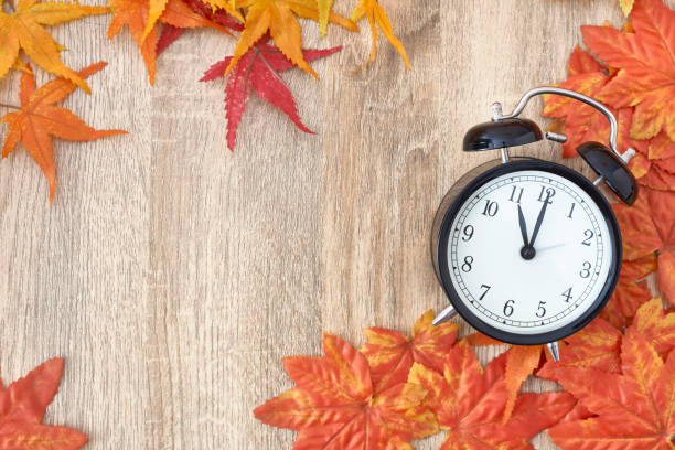 istock Old clock on autumn leaves on wooden table 1135521907