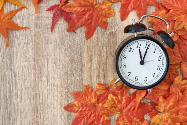 istock Old clock on autumn leaves on wooden table 1135521938