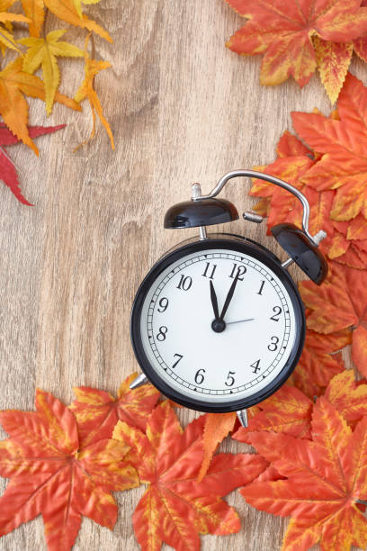 istock Old clock on autumn leaves on wooden table 1135521946