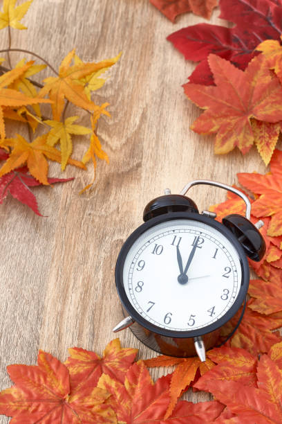 istock Old clock on autumn leaves on wooden table 1135521978