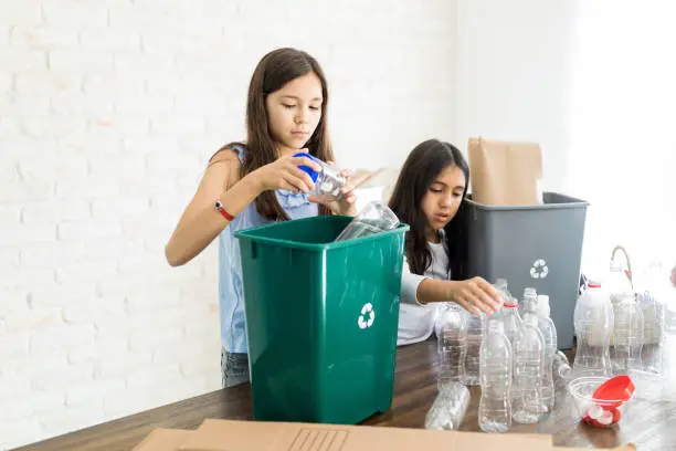 Photo of Girls Throwing Plastic Thrash In Recycling Bins