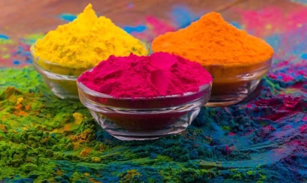 Holi color powder. Organic Gulal colours in bowl for Holi festival, Hindu tradition festive. Blue, pink, magenta, orange, yellow holi dry paints on wood desk background stock photo