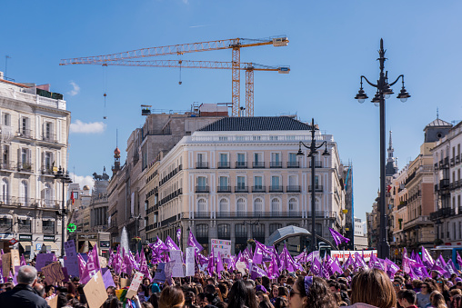 A crowd of people, most of them women wearing purple stuff, defending their rights during the international womens day at Puerta del Sol in Madrid city, Spain.