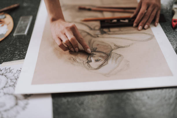 istock Close up of female hand drawing person while using pencil 1135526408