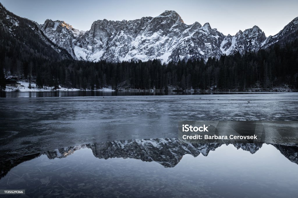 ミラーマウンテンリフレクションとジュリアアルプスの美しい半冷凍フジーネ湖 イタリア Fusine Lakesのストックフォトや画像を多数ご