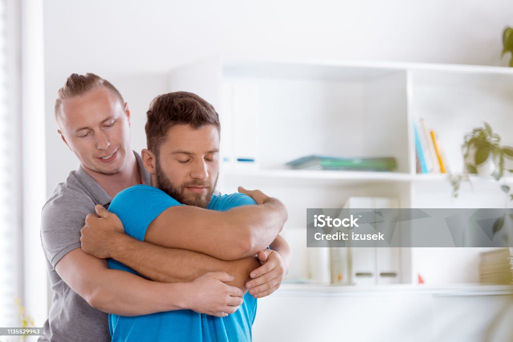 Physiotherapist massaging young man Physical therapist giving back massage to young man. Close up on faces. Chiropractic Adjustment Stock Photo