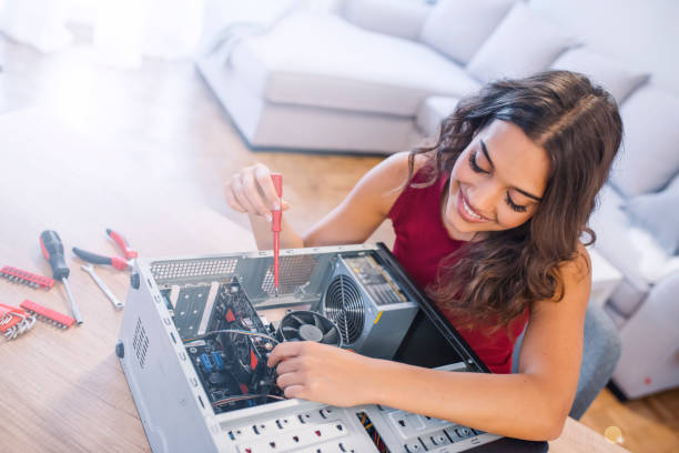 istock Young woman fixing a desktop computer seated at a table at home 1135530745