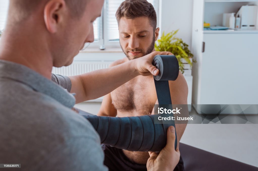 Flossing manual therapy Physical therapist giving floss band to young man. Dental Floss Stock Photo