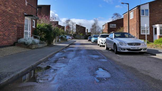 Harlow, England - March 13 2019. A potholed road Harlow, England - March 13 2019. A potholed road leading through a housing estate harlow essex stock pictures, royalty-free photos & images