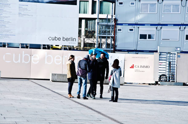 group of friends standing on the walkway outside berlin hauptbahnhof (main train station)  - germany. ad boards (cube berlin and ca immo) at the background - immo imagens e fotografias de stock