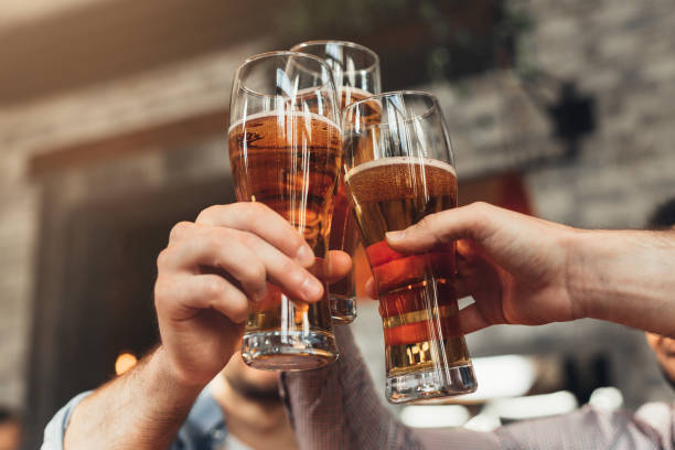 vrienden toasten met glazen bier in de pub - alcohol drinks stockfoto's en -beelden